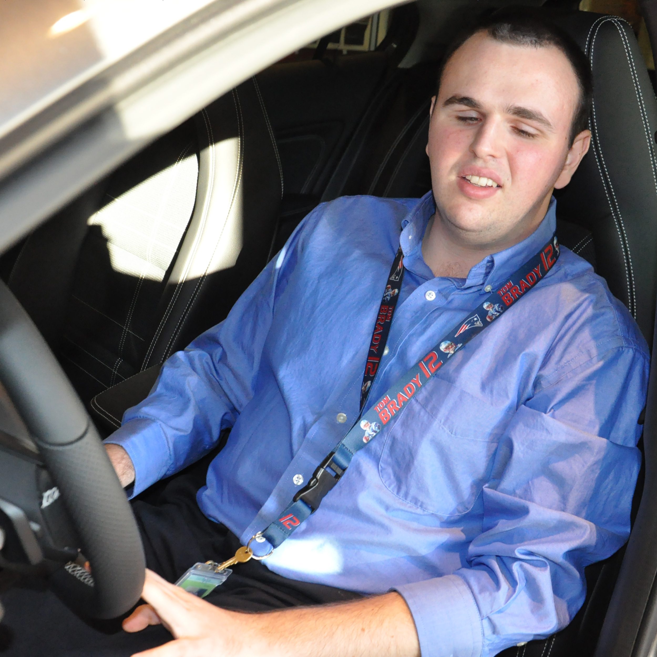 Adam Roberge smiling, sitting in the driver's seat of a car
