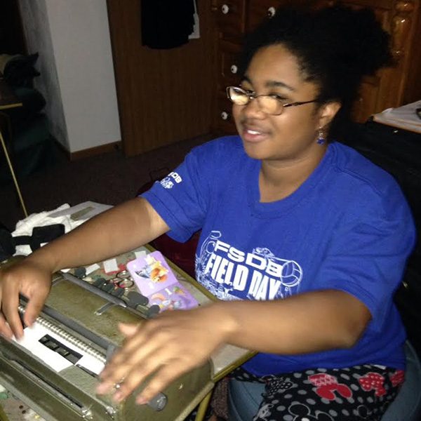 Jasmyn smiles as she works on her brailler