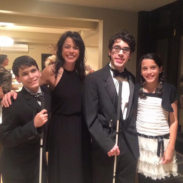 Kristin Smedley and her three children smiling for the camera at a formal event. Her sons, Michael and Mitchell, are holding mobility canes.