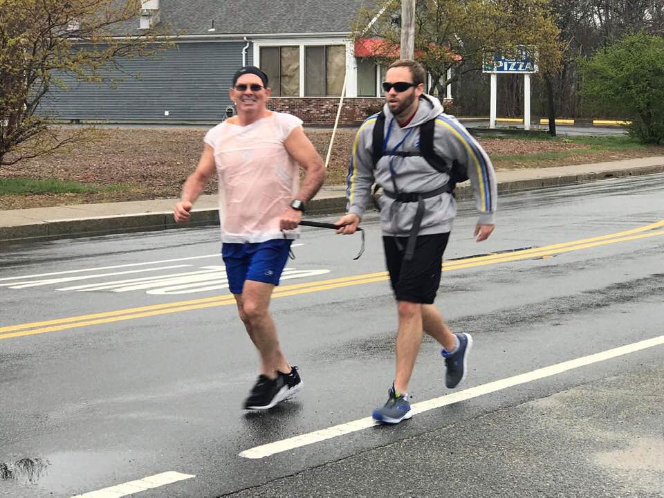Brian and his guide, John Lesperance, jog together on the race course. They're both holding on to a rigid tether that keeps them together and in sync.