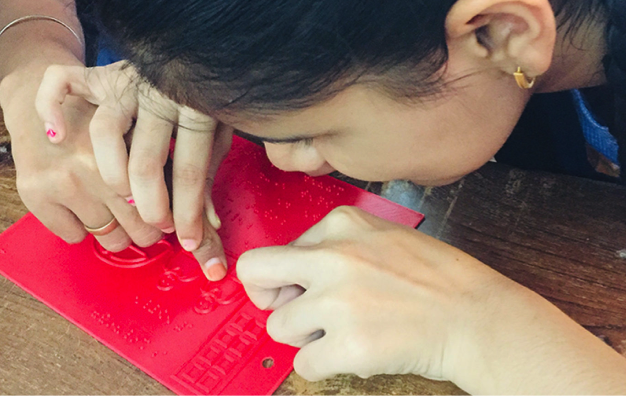 With the guidance of a teacher, a child touches the tactile illustration in a Beyond Braille book.