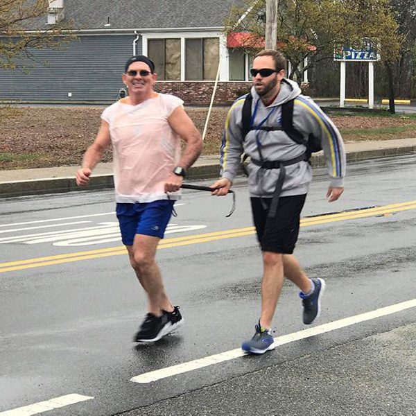 Brian and his guide, John Lesperance, jog together on the race course. They're both holding on to a rigid tether that keeps them together and in sync.