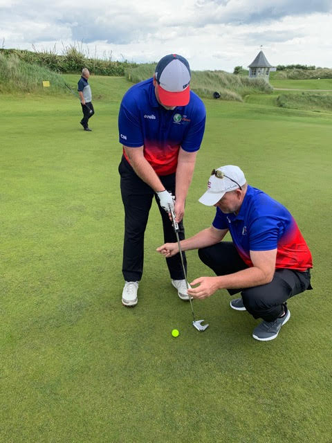 At the 2019 ISPS HANDA VISION CUP set at Portmarnock Links in Dublin, Ireland, Chad NeSmith is about to sink a 15-foot putt with the help of his guide, Andy Church, who snaps his fingers when the ball is lined up and ready to be putt.