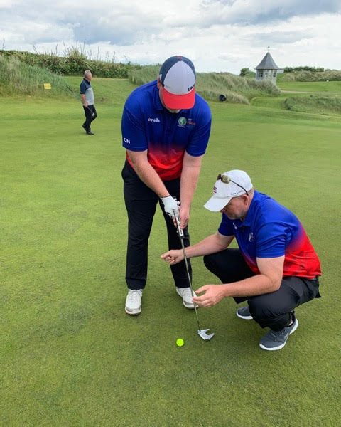 At the 2019 ISPS HANDA VISION CUP set at Portmarnock Links in Dublin, Ireland, Chad NeSmith is about to sink a 15-foot putt with the help of his guide, Andy Church, who snaps his fingers when the ball is lined up and ready to be putt.