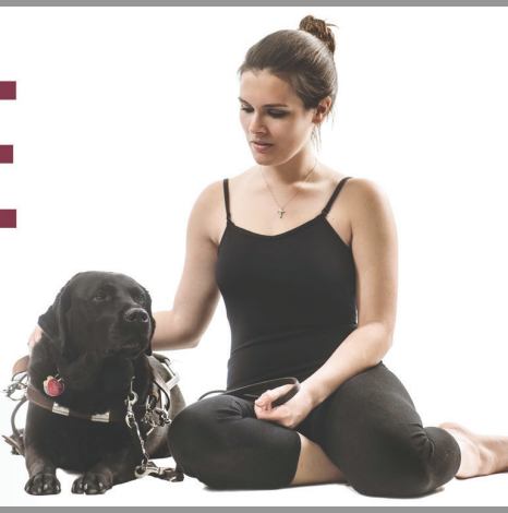 Samantha, dressed in dance gear, sits against a white backdrop with a black Lab guide dog