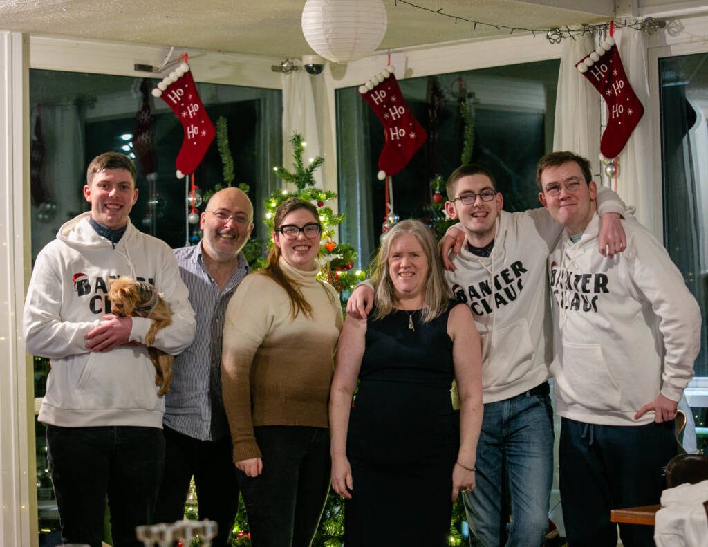 A photo of the Fulham family, taken in front of a Christmas tree and stockings