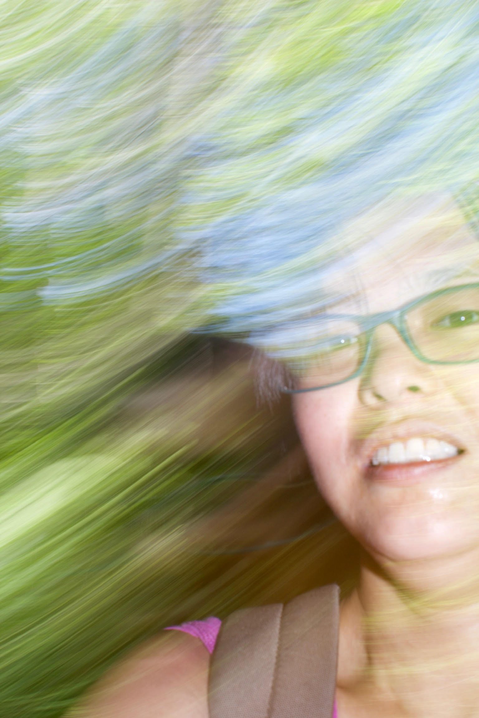 A blurred selfie-style image of Tina Zhu Xi Caruso, a young Asian woman wearing glasses and smiling for the camera